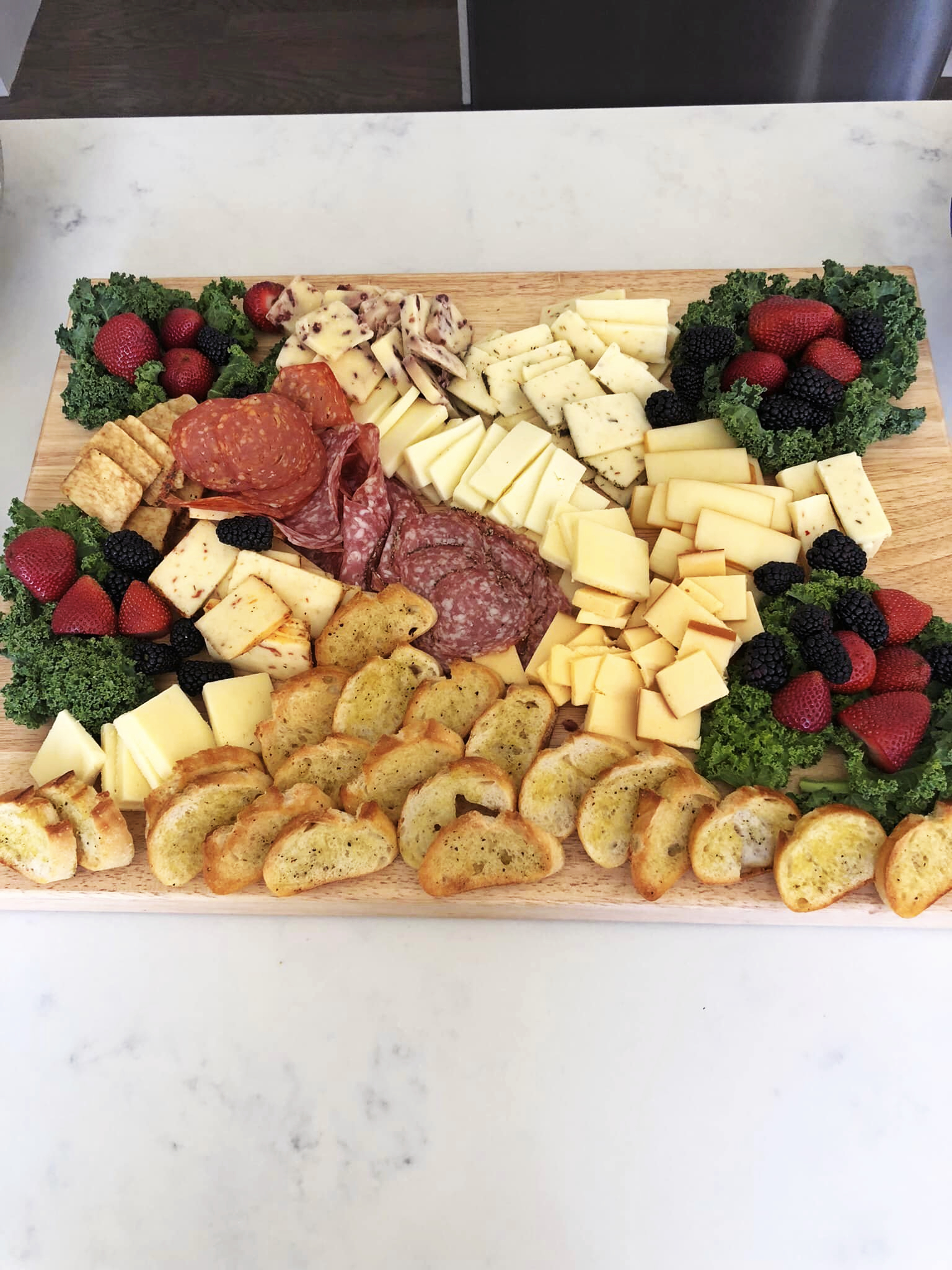 Charcuterie and cheese board with cured meats, berries, and crostini