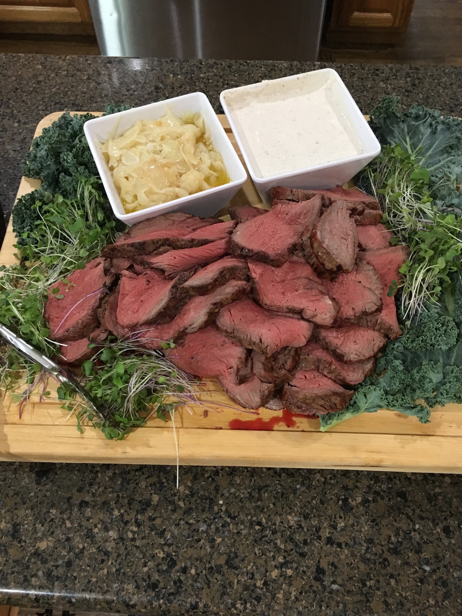 Sliced roast tenderloin board with sweet vidalias, horseradish, and greens
